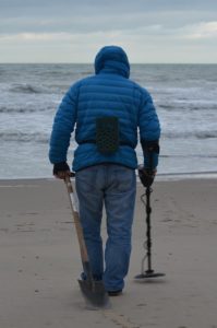 man using Metal Detector on beach